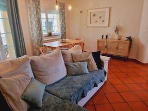 Ein Wohnzimmer mit einer Couch, einem Esstisch und einem Schrank.