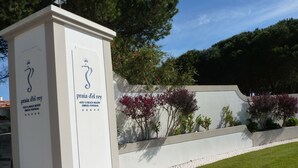A white sign with the logo and name of Praia del Rey, a golf and beach resort in Portugal. - Obidos - Resort 5 * - Praia D'El Rey - Surf Golf & Beach - 2 bedroom apartment (Amoreira)