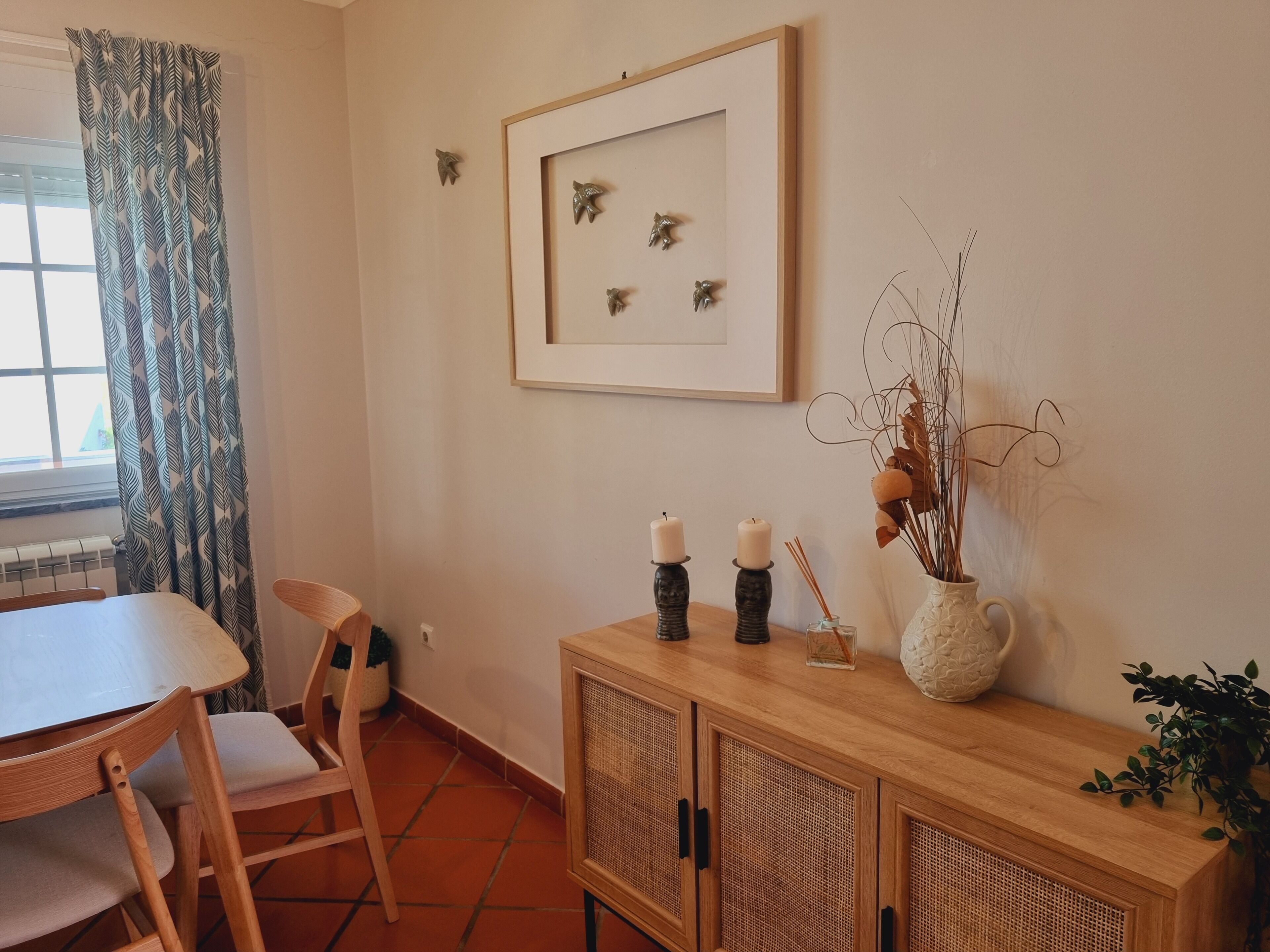 A dining area with a table, chairs, a cabinet with decorative items, and a framed picture on the wall.