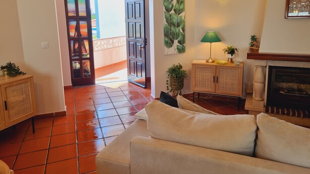 A living room with a sofa, a cabinet, a fireplace, and a door leading to an outdoor area. - Obidos - Resort 5 * - Praia D'El Rey - Surf Golf & Beach - 2 bedroom apartment (Amoreira)