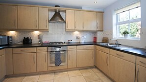 Una cucina moderna con mobili in legno, piano cottura a gas, forno integrato e una finestra che lascia entrare luce naturale.
