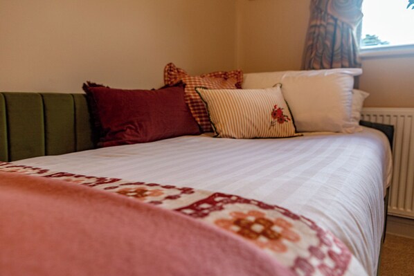 A bed with a patterned bedspread and multiple pillows.