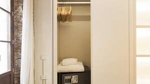 A walk-in closet with a hanging rod, a folded towel, and a black electronic device on a shelf.