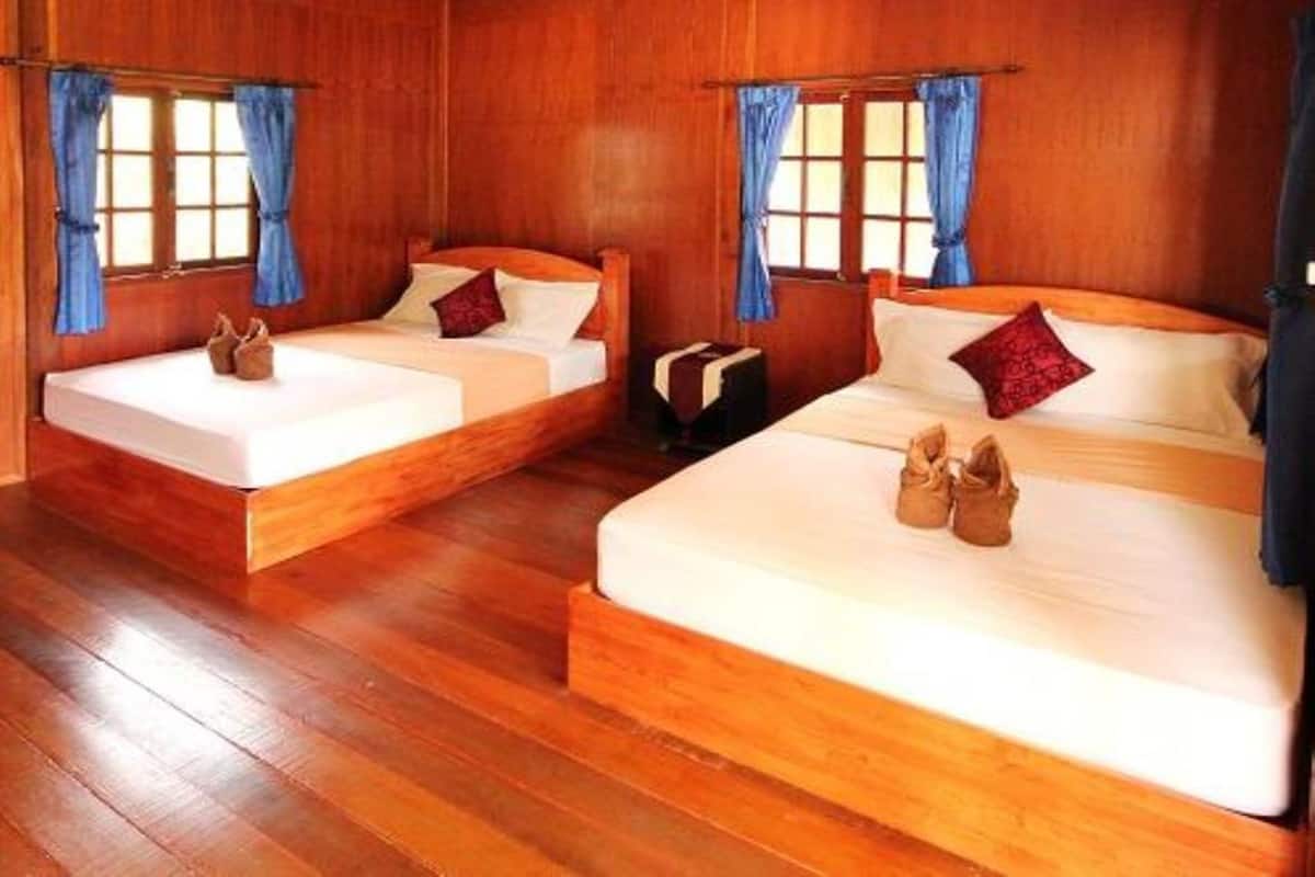Una habitación con dos camas de madera, cada una con un almohadón y un par de zapatos encima.