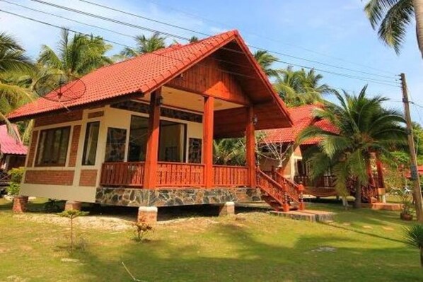 Ein Bungalow mit rotem Dach, einer Veranda und einem Steinfundament.