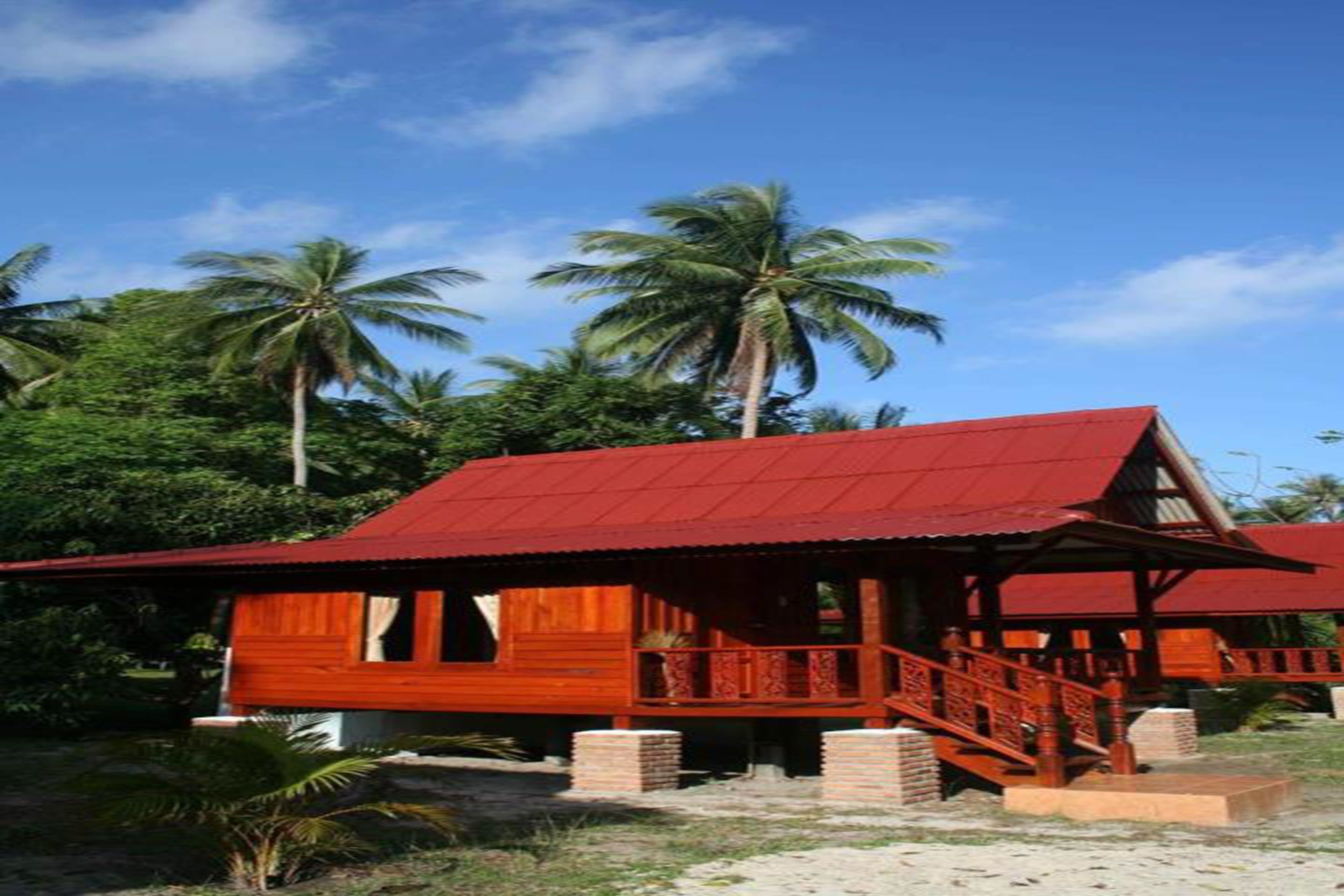Un edificio de madera con techo rojo, rodeado de palmeras.