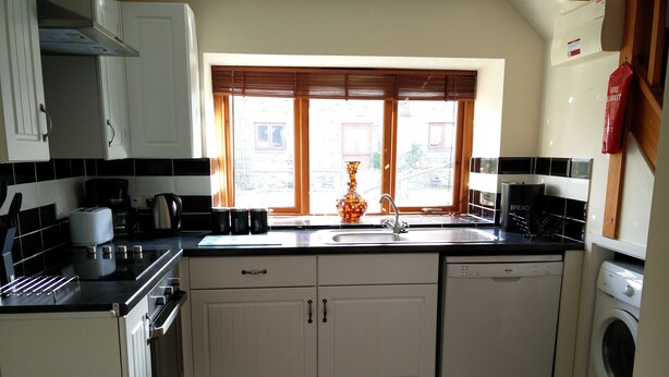 A kitchen with white cabinets, a built-in oven, a dishwasher, a microwave, and a window with blinds. - Fantastic couples escape to the country. Quiet, rural location, pet friendly. (Boncath)