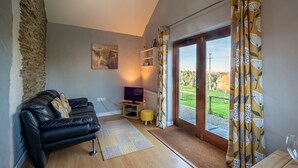 A modern living room with a black leather sofa, a small TV, and a wooden coffee table. - Fantastic couples escape to the country. Quiet, rural location, pet friendly. (Boncath)