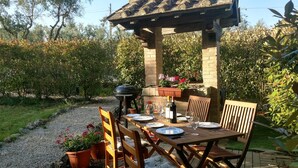An outdoor patio with a wooden table set for dining, surrounded by wooden chairs and a barbecue grill. - 2 bedrooms, large pool, stunning views of San Gimignano, Tuscany, private garden (San Gimignano, Tuscany)