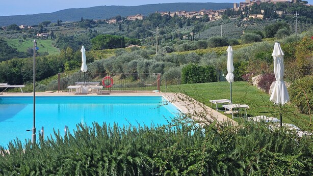 A pool area with a view of a historic hilltop town. - 2 bedrooms, large pool, stunning views of San Gimignano, Tuscany, private garden (San Gimignano, Tuscany)