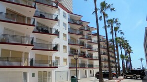 Un hôtel à plusieurs étages doté de balcons, d’un parking et de palmiers.