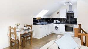 A compact kitchen with a dining area, including a table set for two, a washing machine, and a built-in oven. - Fantastic couples escape to the country. Close to the coast in peaceful location (Boncath)