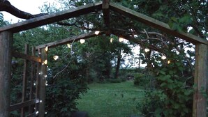 A wooden archway with string lights, surrounded by greenery and a grassy area. - Fantastic couples escape to the country. Close to the coast in peaceful location (Boncath)