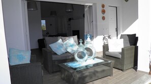 An outdoor seating area with wicker furniture, a glass coffee table, and decorative items.