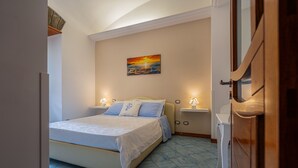 Ein Schlafzimmer mit einem Bett, Nachttischlampen, einem Wandbild und einem Fliesenboden.