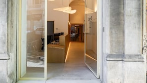 Un intérieur moderne avec une entrée dotée d’une porte en verre, un comptoir d’accueil et un espace de bureaux visible.