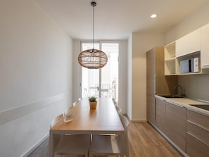 Una cocina moderna con armarios de madera, microondas integrado y una lámpara colgante.