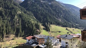 A mountain village with buildings surrounded by forest and snow-capped peaks. - Hotel Garni Central (Kappl)