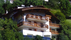 A multi-story building with balconies, surrounded by lush greenery. - Hotel Garni Central (Kappl)