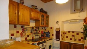 Cocina compacta con armarios de madera, salpicadero azulejado, lavadora y un lavamanos pequeño.