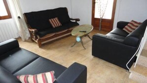 Una sala de estar con un sofá negro, un sofá de madera y una mesita redonda.