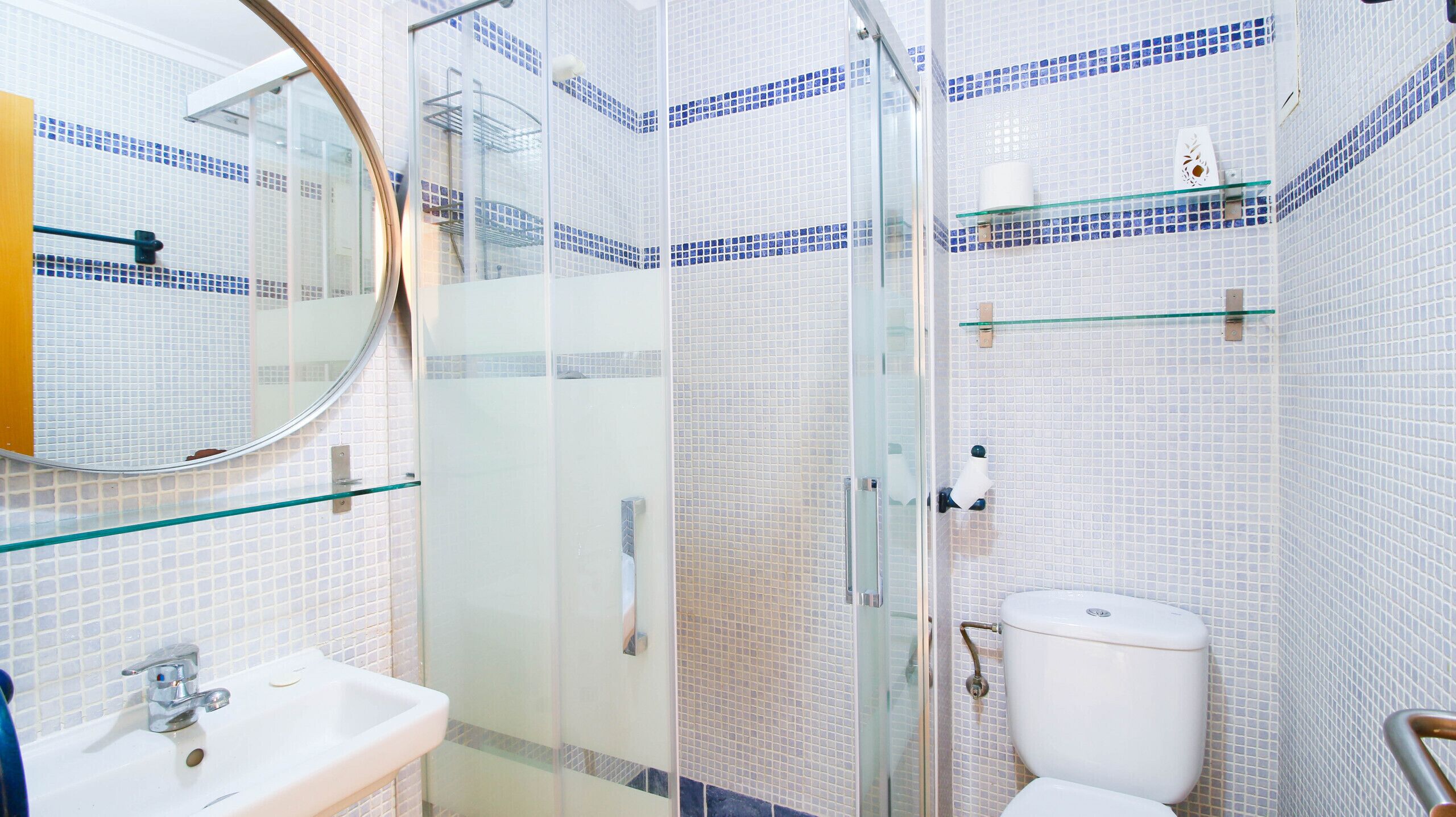 Une salle de bain avec une douche à parois de verre, un lavabo blanc et des toilettes.