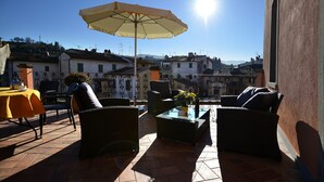 Eine Terrasse im Freien mit Korbmöbeln, einem gelben Tisch und einem Sonnenschirm.