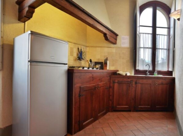 A kitchen with wooden cabinets, a white refrigerator, and a window with a view. - Three bedrooms apt. F in a Old Pasta factory with shared pool (Greve in Chianti)