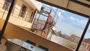 A covered outdoor area with a table and chairs, a spiral staircase, and a view of a building with a dome. - B&B Casa Italia (Timisoara)
