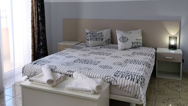 A modern bedroom with a large bed, a bedside table with a lamp, and a picture on the wall. - B&B Casa Italia (Timisoara)