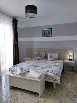 A modern bedroom with a large bed, a bedside table with a lamp, and a picture on the wall. - B&B Casa Italia (Timisoara)