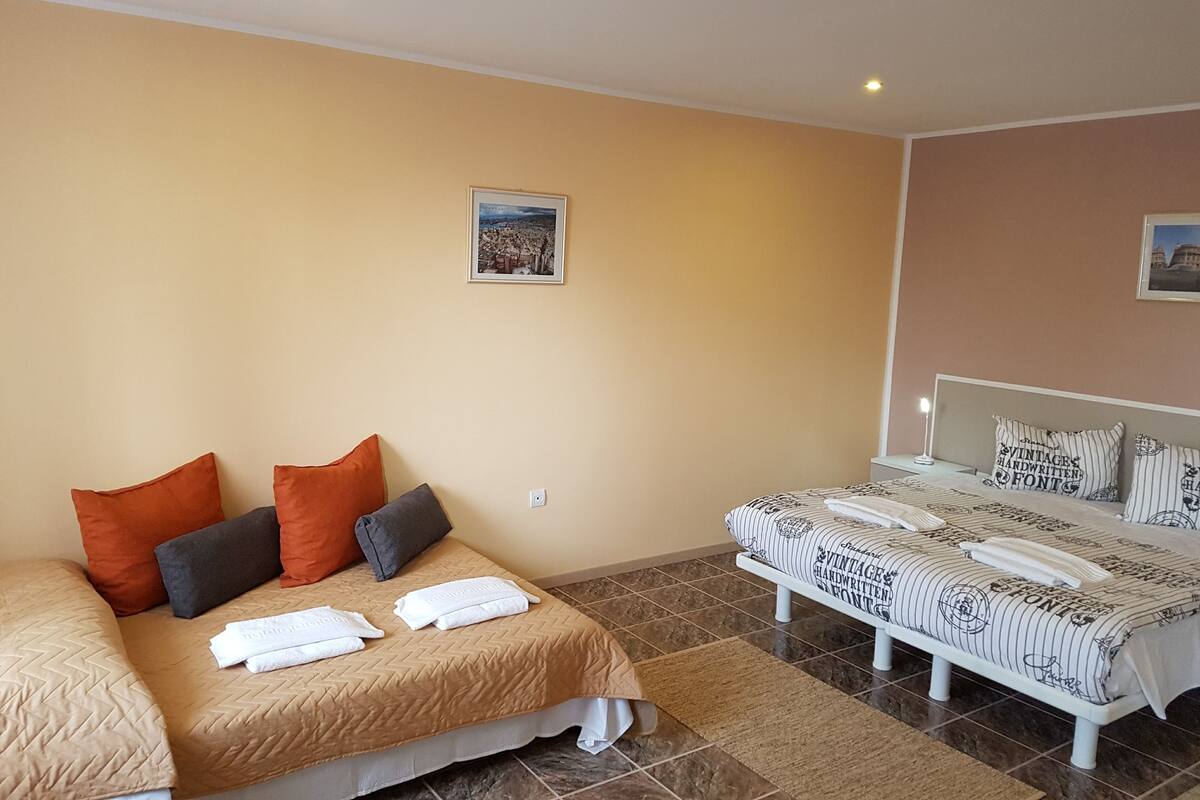 A hotel room with a large bed, a smaller bed, and a view of a cityscape.