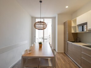 A modern kitchen with wooden cabinets, a built-in microwave, and a hanging light fixture. - SUPERIOR 4 BEDROOM APARTMENT (Barcelona)