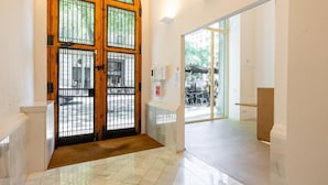 A hallway with a wooden door with glass panels, a tiled floor, and a view of an outdoor seating area. - SUPERIOR 4 BEDROOM APARTMENT (Barcelona)
