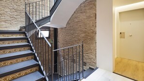 A staircase with a brick wall and a modern design, leading to a room with a door marked '31'. - Deluxe One Bedroom Apartment (Barcelona)