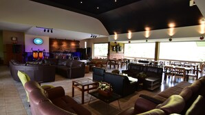 A spacious lounge area with leather sofas, a coffee table, and a stage with musical instruments. - Mamaungpaa Hillside Resort (Takhli)