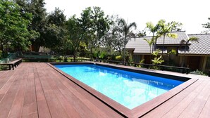 A rectangular swimming pool with a wooden deck surrounding it. - Mamaungpaa Hillside Resort (Takhli)