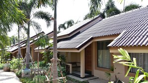 A row of traditional-style villas with tiled roofs, surrounded by lush greenery and palm trees. - Mamaungpaa Hillside Resort (Takhli)