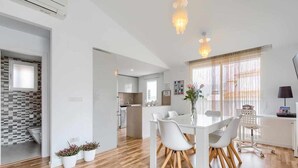 Eine moderne Küche mit weißen Schränken, einem eingebauten Backofen und einer großen Kochinsel mit Sitzgelegenheiten.