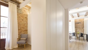 Un intérieur moderne avec des murs en briques apparentes, des poutres en bois et un coin repas comprenant une table et des chaises.