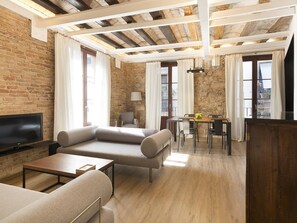 Un soggiorno moderno con una televisione a schermo piatto, un divano, un tavolo da pranzo con sedie e una parete in pietra.