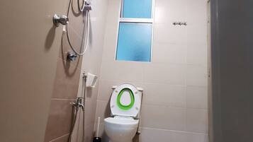 A small bathroom with a toilet, a shower, and a window.
