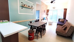 A modern living space with a dining area, a sofa, and a kitchen area with a brick wall and pendant lights. - The Woodz Homestay (Tanah Rata)