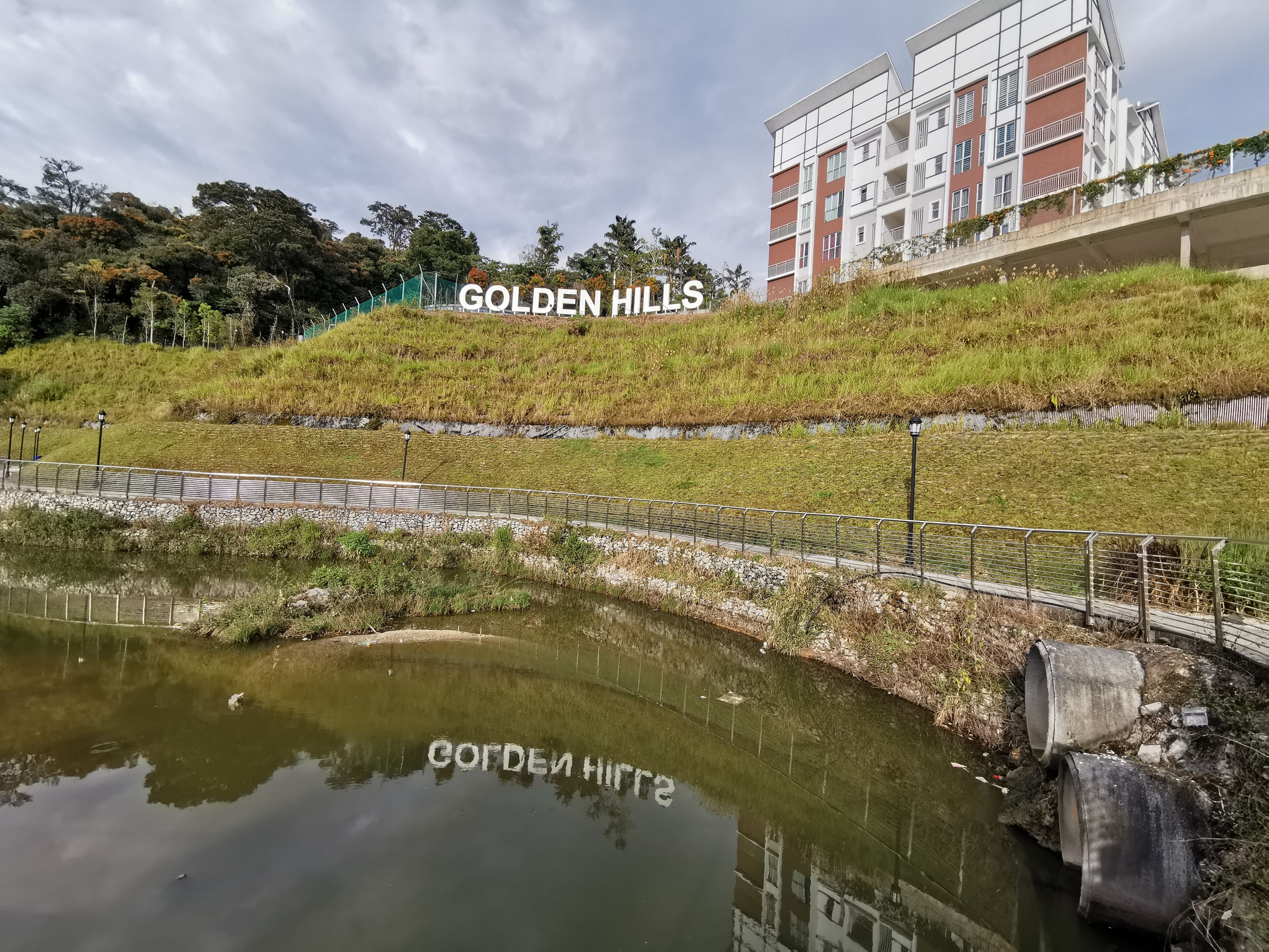 Een woongebied genaamd Golden Hills, met een waterpartij, een brug en een meerhoog gebouw.