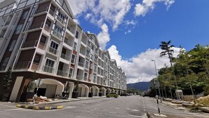 A multi-story residential building with balconies, a covered walkway, and a clear sky. - The Woodz Homestay (Tanah Rata)