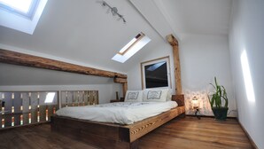 A bedroom with a wooden bed, skylight, and a potted plant. - Beautifully designed Apartment.  Fully equipped for your holiday needs. Sleeps 7 (Interlaken)