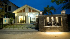 Een moderne villa met een goed verlichte entree, een gevel van natuursteen en een vrij uitzicht op de naam van het landgoed.