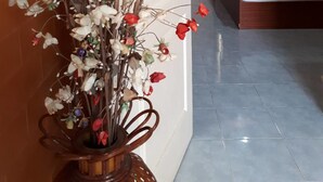 A room with a bed, a wall-mounted air conditioner, and a decorative vase with artificial flowers. - Chainam Resort (Chaloem Phra Kiat)