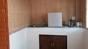 A kitchen with a white refrigerator, a sink, a kettle, and a toaster. - Chainam Resort (Chaloem Phra Kiat)