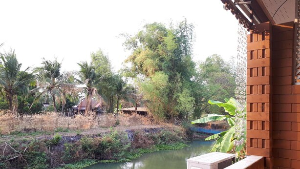 A view of a river with surrounding vegetation and a brick structure. - Chainam Resort (Chaloem Phra Kiat)